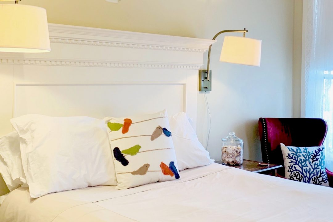 Bed with white headboard and colorful pillow